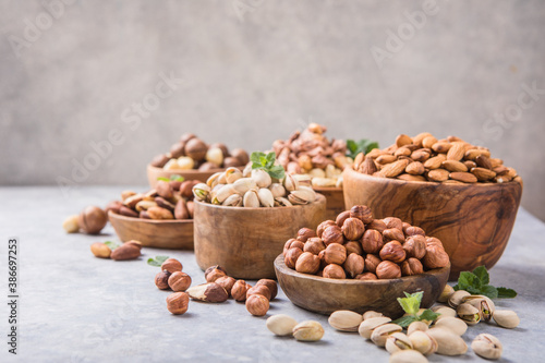 Assortment of nuts in a wooden bowls, on a gray background. Hazelnuts, pistachios, almonds, brazil nut, cashews