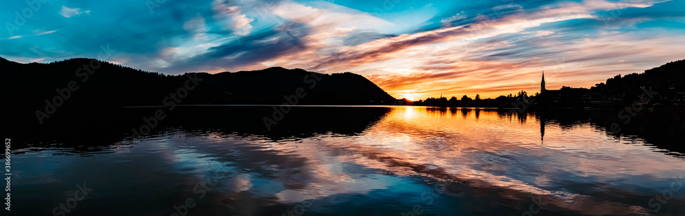 High resolution stitched panorama of a beautiful alpine sunset view with reflections and dramatic clouds at the famous Schliersee, Bavaria, Germany