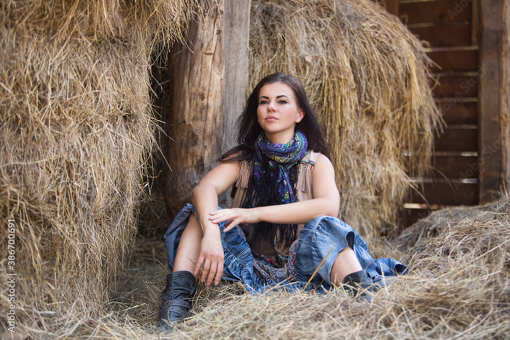 Beautiful hippie girl sitting on a haystack. Modern boho style. Beauty, fashion. Beautiful hippie girl sitting on a haystack. Modern boho style. Beauty, fashion.