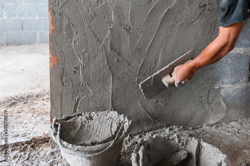 closeup hand of worker plastering cement at wall in construction site photo