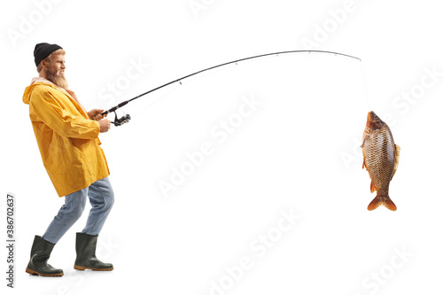 Full length profile shot of a bearded fisherman catching a big fish