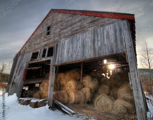 Old barn with hay bales with snow in winter