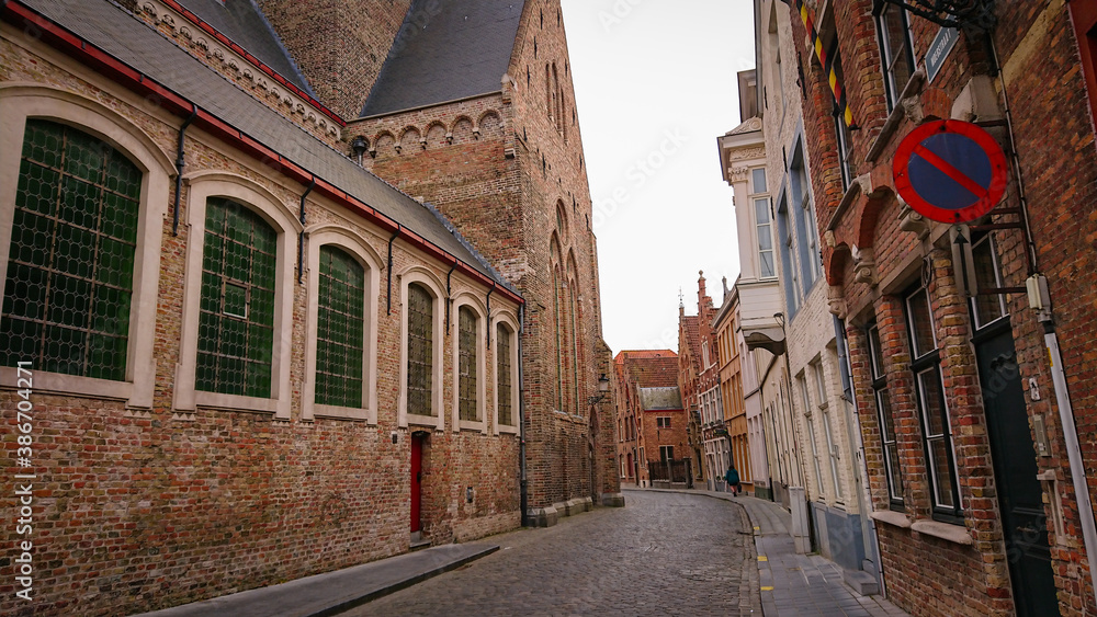 Fototapeta premium Bruges, Belgium - May 12, 2018: Roofs And Windows Of Old Authentic Brick Houses On Street Sint-Jakobsstraat