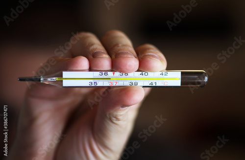 Mercury thermometer in hand with normal temperature 36.6, close-up photo