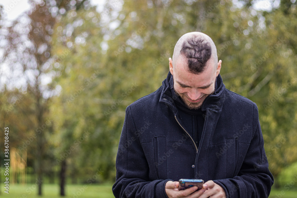 A man looks at his phone and smiles in a park A man looks at his phone and smiles in a park