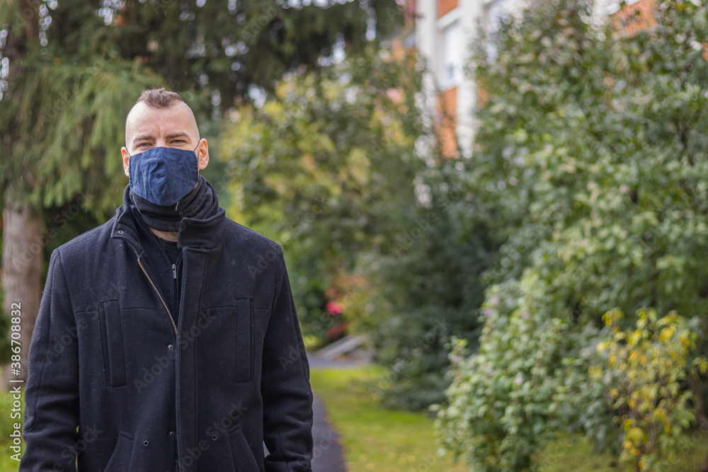 A man walks in the dripping rain while wearing a mask in a small city in Hungary A man walks in the dripping rain while wearing a mask in a small city in Hungary