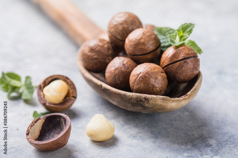 Pile macadamia nuts open kernels and shells in spoon on concrete background. Pile macadamia nuts open kernels and shells in spoon on concrete background.