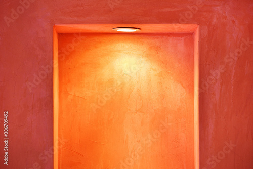 窪みのある赤土の塗壁と埋め込まれたダウンライトの素材イメージ