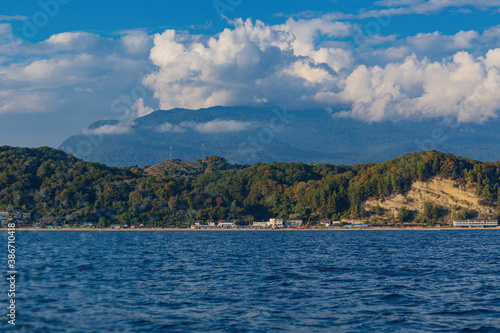 View from the sea on a boat to the city near the mountains with beautiful clouds . © viktor