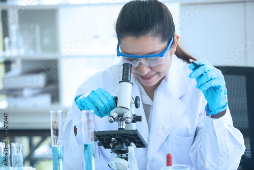 Asian woman scientist researcher using microscope in laboratory. Medical healthcare technology and pharmaceutical research and development concept.