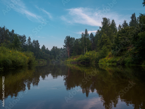 Mirror surface of the river water surface in the middle of the forest. Silence in unique natural locations far from civilisation.