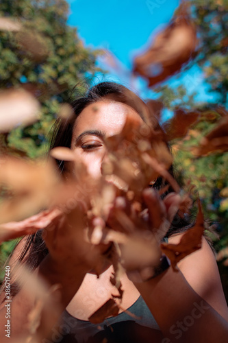 Young woman blowing fallen leaves on a sunny day - Autumn fall colorful season © Fred