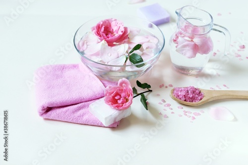 Fresh pink roses  water  petals  candles on a light background  body care products  natural home cosmetics  healthy lifestyle  alternative medicine