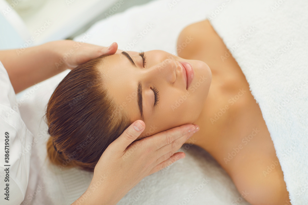 Smiling womans face getting professional manual relaxing massage from hands of masseur Smiling womans face getting professional manual relaxing massage from hands of masseur