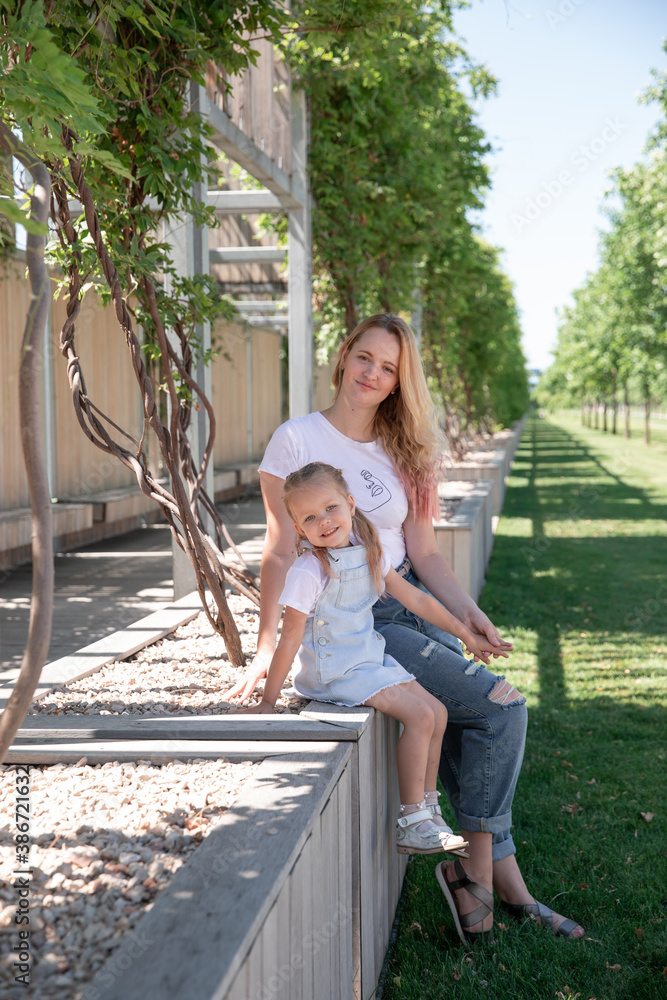 Fototapeta premium Beautiful mother and little daughter walking together in summer park
