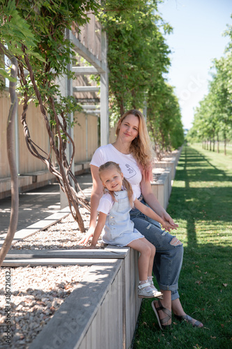 Beautiful mother and little daughter walking together in summer park