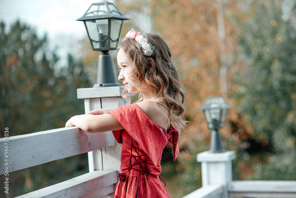 A beautiful little girl in a long red dress with a hoop on her head ...