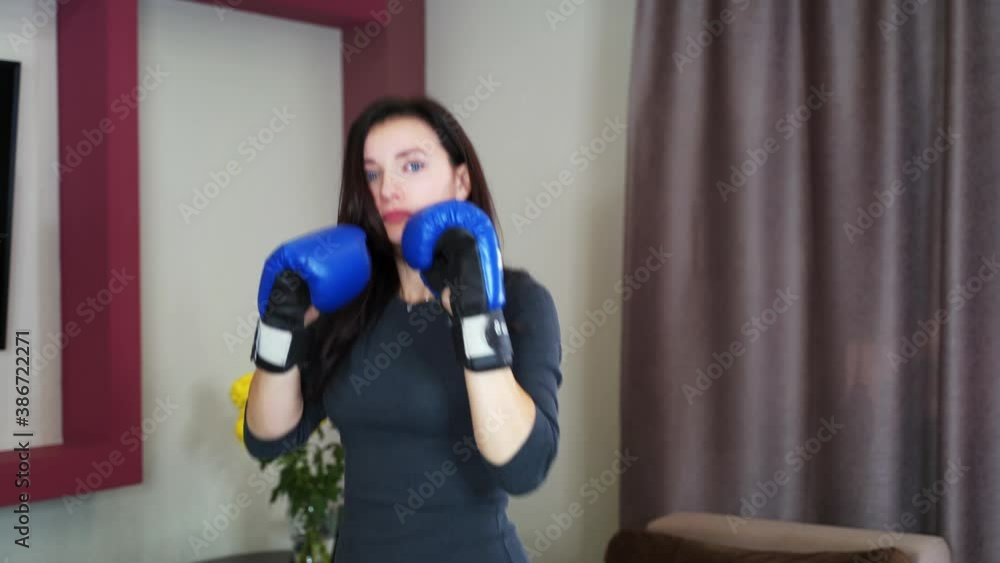 Young girl housewife boxing at home in the air with blue boxing gloves. 4k Young girl housewife boxing at home in the air with blue boxing gloves. 4k