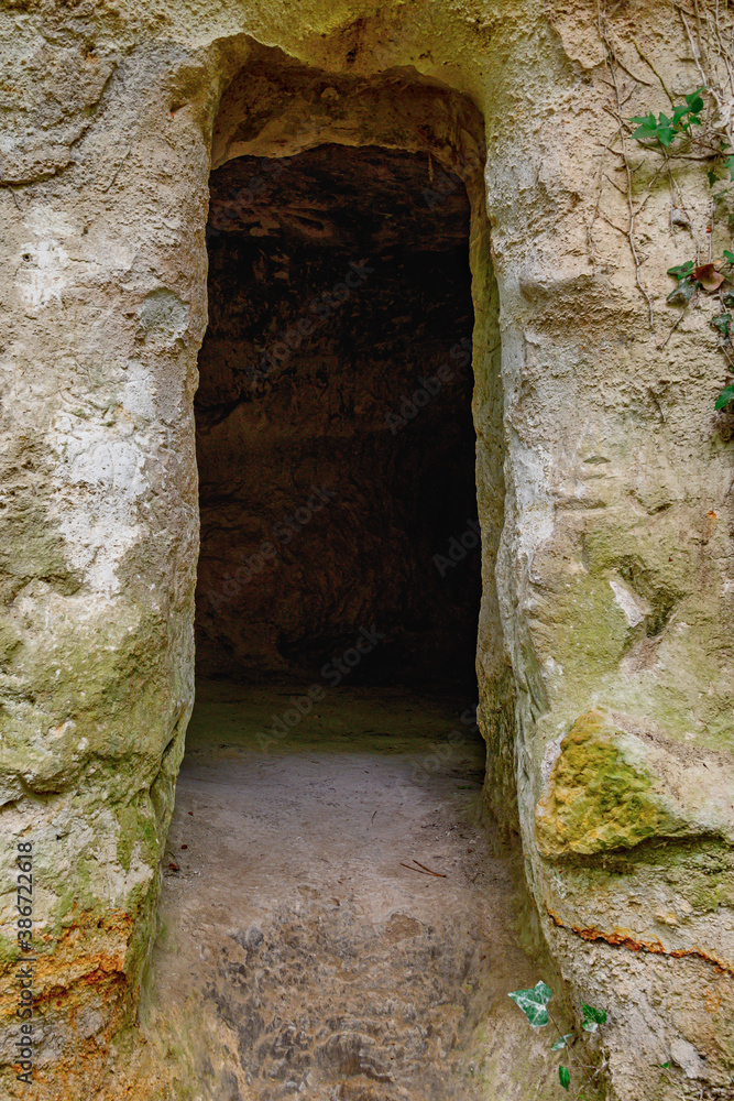 Close-up of an open doorway in the rock. You can see the dark entrance and on the sides the rock wall. Former home of a hermit