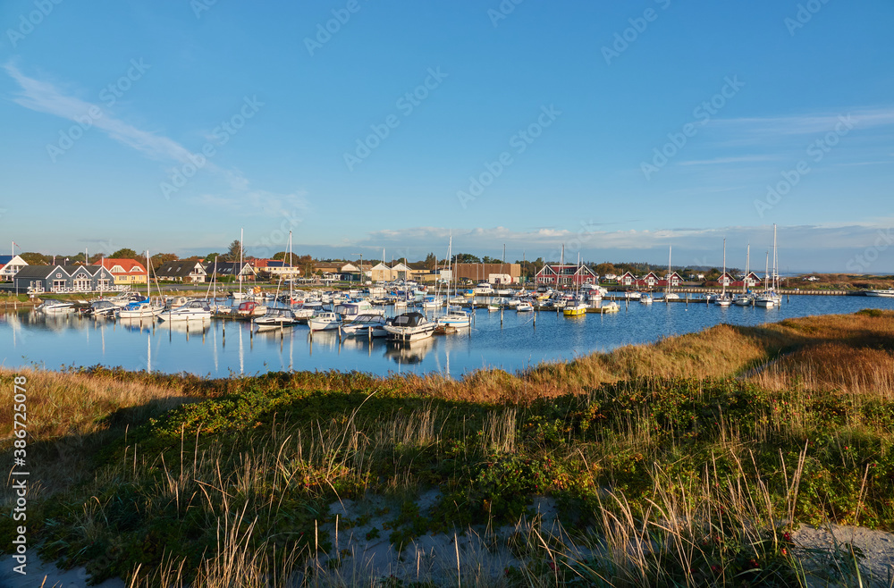 View of the yacht harbor of Hou, the sailing boats are attached to the pier and in the background you can see many holiday homes. Taken from a dune. Denmark, Hou.