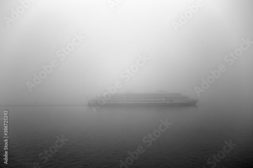 A large motor ship goes along the river in a thick fog. Dense fog on the river.  photo