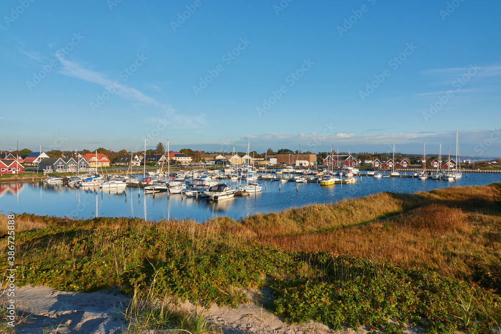 View of the yacht harbor of Hou, the sailing boats are attached to the pier and in the background you can see many holiday homes. Taken from a dune. Denmark, Hou.