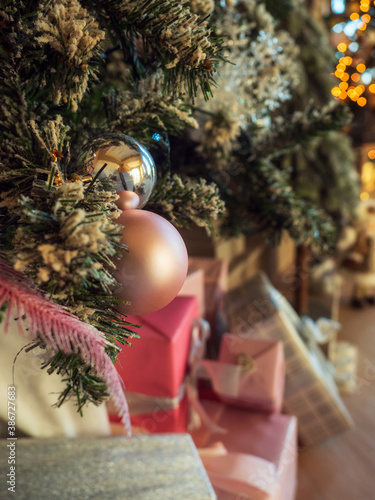 Christmas toy pink ball hanging on green branches. close up