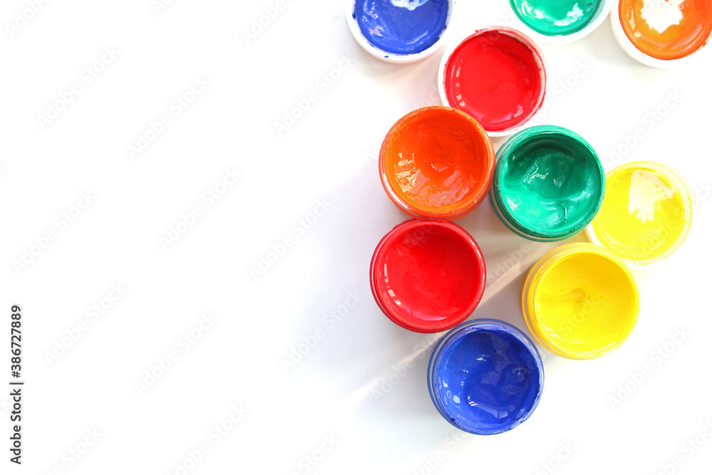 Open gouache jars on white background,top view.Copy space.advertising of master classes for painting and drawing lessons Open gouache jars on white background,top view.Copy space.advertising of master classes for painting and drawing lessons