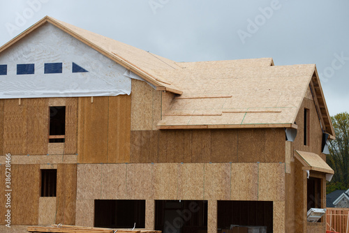 covering the roof of a new wooden house with plywood wall