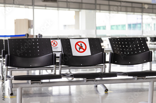 Empty waiting room at an airport during COVID-19 pandemic with social distancing signs on chairs
