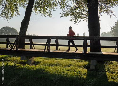 Läufer auf Holzsteg über Wiese, Morgenstimmung photo