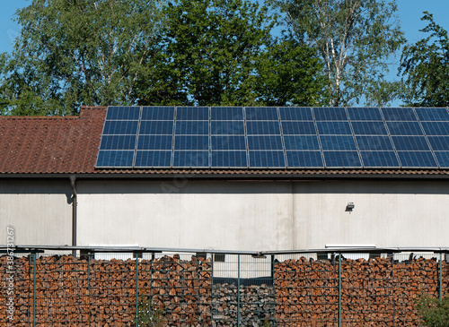 Solarpanels auf Scheunendach, davor Stapel mit Brennholz photo