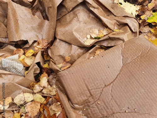 Crumpled wrapping paper and recycled cardboard boxes lie outside in the wet autumn foliage.