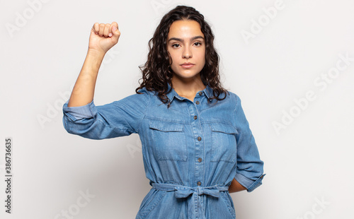Obraz na plátně pretty young woman feeling serious, strong and rebellious, raising fist up, prot