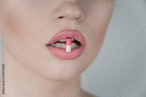 Pill between lips. Close up young woman with medicine pill in her sensual mouth