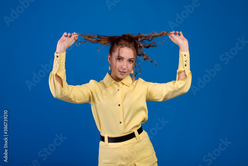 Pretty surprised lady in yellow pants fooling around in the studio and jumping. Pin-up girl dancing on a colorful background