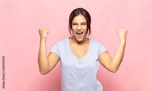 pretty young woman shouting aggressively with an angry expression or with fists clenched celebrating success