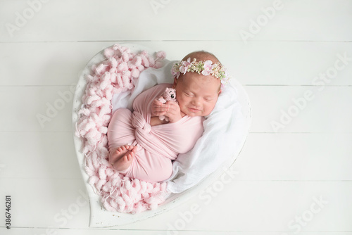 Little newborn baby girl sleeping with a soft toy in his hands, newborn photoshoot