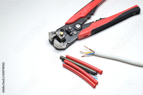 wire stripper, shielded three-core wire and heat shrink tubing on a white background. close-up