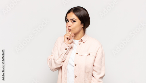 pretty young woman asking for silence and quiet, gesturing with finger in front of mouth, saying shh or keeping a secret photo