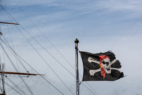 Foto A jolly roger or skull and crossbones flag flying in front of the mast of an old