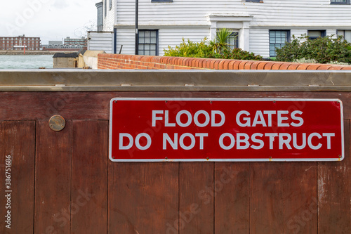 Flood gates shielding a home from flood waters with the sign reading flood gates do not obstruct