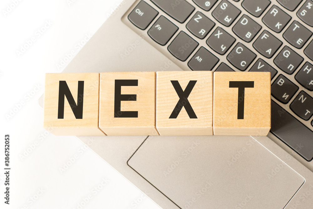 Word next. Wooden cubes with letters isolated on a laptop keyboard. Business Concept image. Word next. Wooden cubes with letters isolated on a laptop keyboard. Business Concept image.