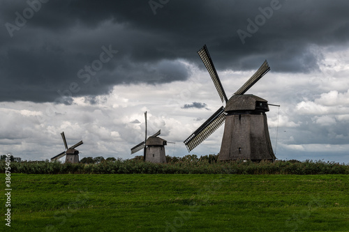 Three windmills with dark sky above
