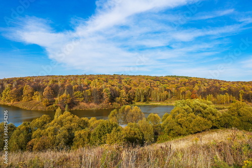 autumn landscape of lake and orange forest on the slope. panoramic view of the forest river on a sunny autumn day