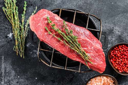 Raw Striploin steak on a grill, marbled beef. Black background. Top view