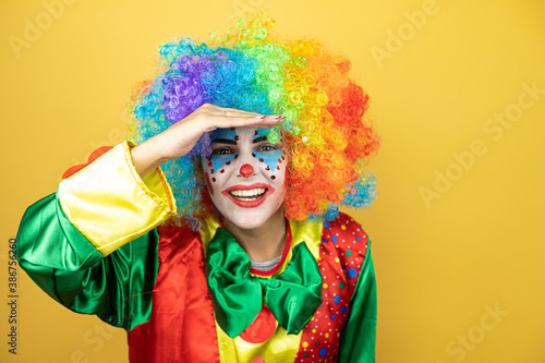 Clown standing over yellow insolated yellow background looking for something