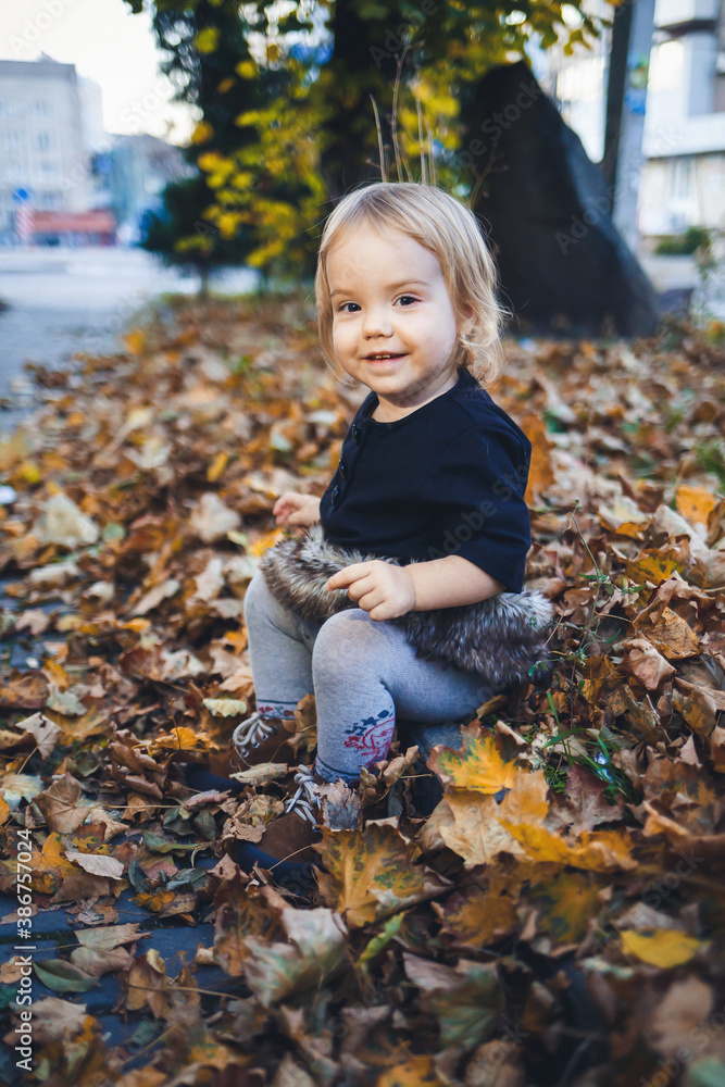 A little girl of 1.5 years is standing and smiling. The child throws leaves. Cheerful girl in the autumn forest A little girl of 1.5 years is standing and smiling. The child throws leaves. Cheerful girl in the autumn forest