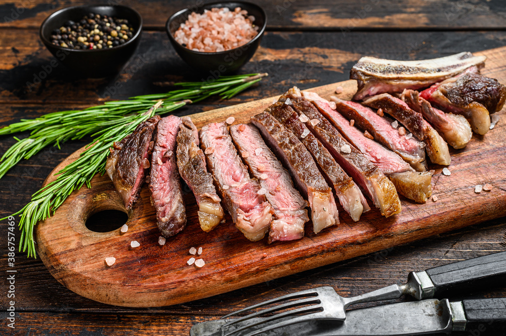 Ribeye steak on the bone. Grilled Beef meat.  Wooden dark background. Top view