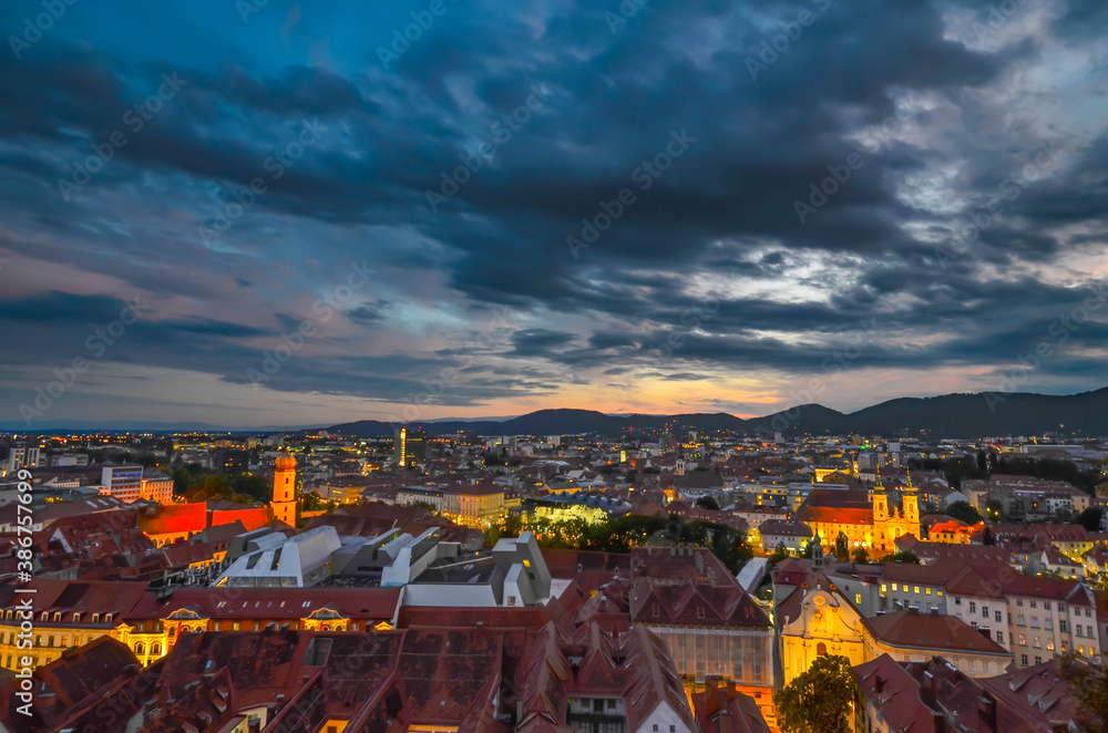 City lights of Graz and Mariahilfer church, view from the Schlossberg hill, in Graz, Styria region, Austria, after sunset. Dramatic sky, panoramic view.